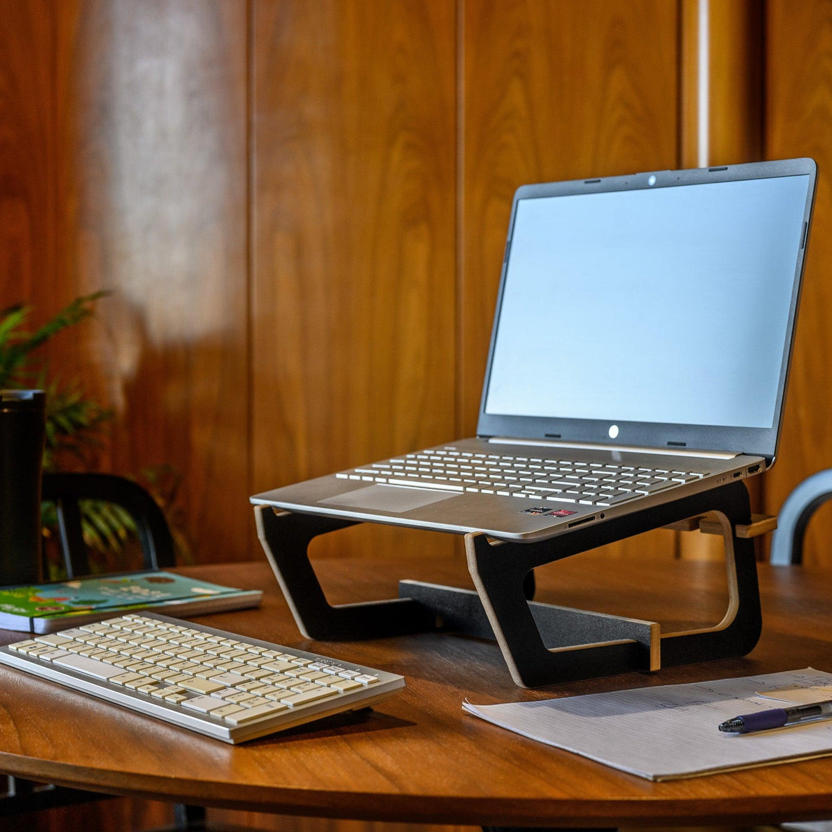 Υπερυψωμένη μαύρη βάση laptop σε πραγματικό χώρο εργασίας
